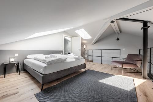 a white bedroom with a large bed and a chair at Stay COOPER l CITY LOFT in Bolzano