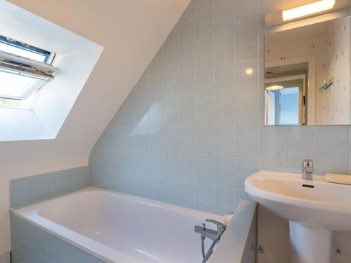 y baño con bañera blanca y lavamanos. en Villa Locmariaquer, 3 pièces, 4 personnes - FR-1-477-36, en Locmariaquer