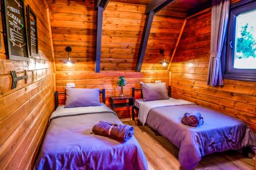 Duas camas num quarto com paredes de madeira em UĞURLUBUNGALOV em Sapanca