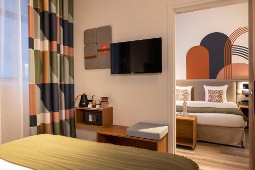 a hotel room with two beds and a flat screen tv at La Belle Ville in Paris