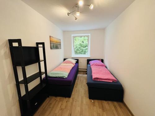 two beds in a small room with a window at Cosy Apartment I 5Beds I Near VW in Glauchau