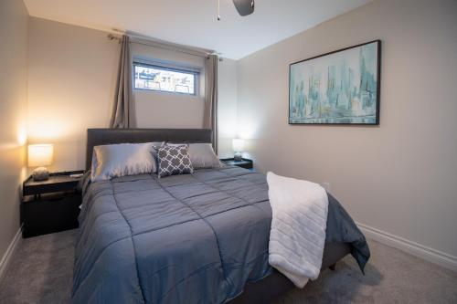 a bedroom with a bed with a blue blanket and a window at Bright private suite near Departure Bay beach in Nanaimo