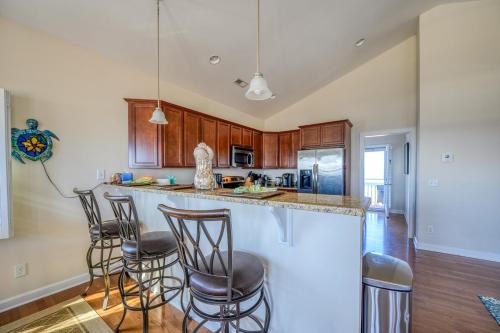 a kitchen with wooden cabinets and a bar with stools at North Topsail Beach Rental- Water Views - Elevator - Dogs Allowed w added fee in North Topsail Beach
