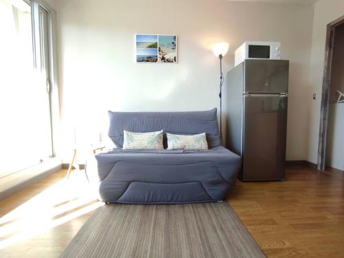 - un canapé bleu dans le salon avec un réfrigérateur dans l'établissement Appartement rénové, calme 300m plage, avec parking et balcon – Beg Meil, Fouesnant - FR-1-481-55, à Fouesnant