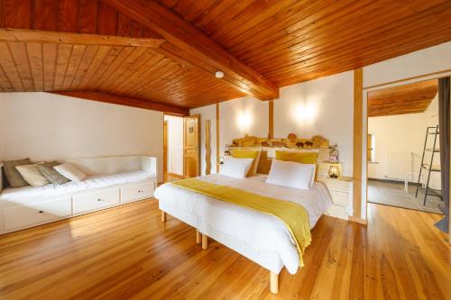 a bedroom with a large white bed and wooden ceilings at Le Fournia in Grandrif