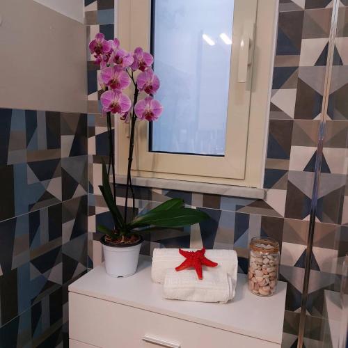 a bathroom with towels and a flower on a shelf at Blue Sicily Apartment in Roccalumera