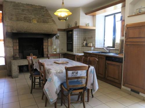 une cuisine avec une table et des chaises ainsi qu'une cheminée dans l'établissement Maison bretonne avec jardin à 50m de la baie Ste Anne - FR-1-368-252, à Trégastel