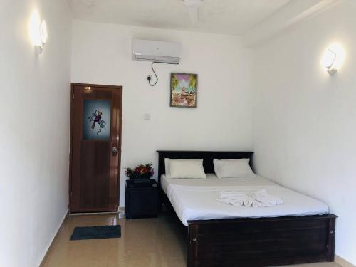 a bedroom with a bed with white sheets and a door at Nilan Villa in Koggala