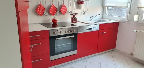 a red kitchen with a stove and a sink at Ferienwohnungen Am Markt in Rüdesheim am Rhein