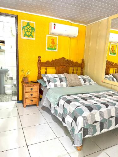 a bedroom with a bed and a yellow wall at Pousada & Camping Tubarão in Ilha do Mel