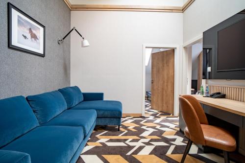 a living room with a blue couch and a table at Santa Natura Resort & SPA in Nowa Wieś