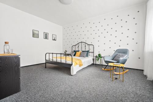 a bedroom with a bed and a chair at Penzion Village Peace #29 by Goodnite cz - U Libušky in Brno