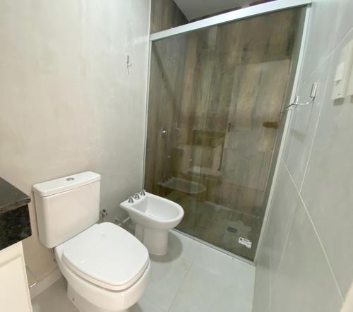 y baño blanco con aseo y ducha. en Victoria Apart & Suites, en Encarnación