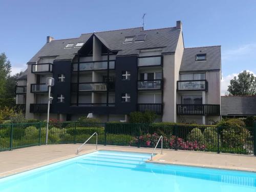 un immeuble avec une piscine devant un immeuble dans l'établissement Appartement 3 pièces rénové avec piscine à Quiberon - Balcon, parking, proche plage - FR-1-478-207, à Quiberon