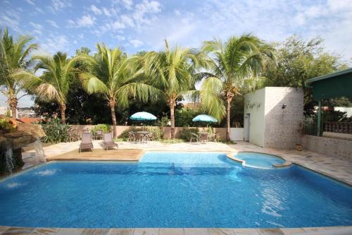 een zwembad met palmbomen op de achtergrond bij Pousada Tia Nena in Olímpia