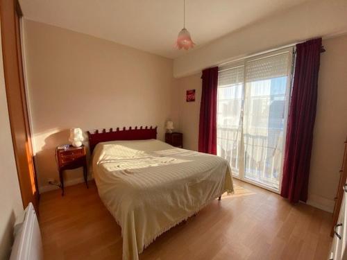 une chambre avec un lit et une grande fenêtre dans l'établissement Appartement T3 Royan, proche de la plage, balcon, dernière étage, cuisine équipée, parking facile - FR-1-494-124, à Royan