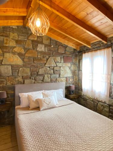 ein Schlafzimmer mit einem großen Bett in einer Steinmauer in der Unterkunft Caviro on the Beach in Moúdhros