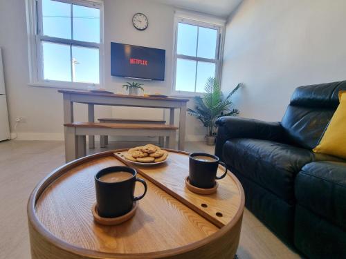 a living room with two cups of coffee on a table at SPACIOUS 3 Bed APARTMENT, EN-SUITES, NEAR TRAIN STATION! in Watford