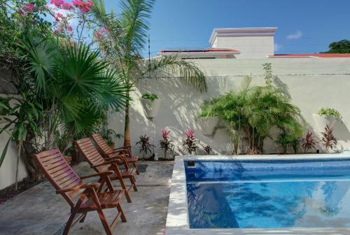 a swimming pool with rocking chairs and palm trees at 5BR Beautiful home in downtown Cancun, 10min beach in Cancún