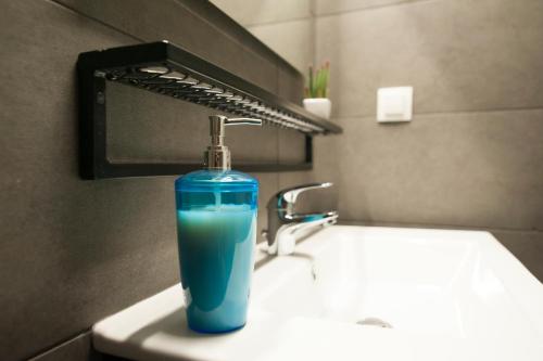 a blue glass bottle sitting on top of a sink at Mazi Rooms Venizelou in Thessaloniki