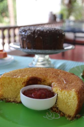 a piece of cake on a green plate with a bowl of jam at Pousada Tia Nena in Olímpia