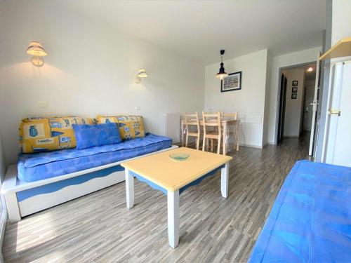 un salon avec un canapé bleu et une table dans l'établissement Appartement à Fouesnant avec piscine chauffée, proche plage et GR34 - FR-1-481-109, à Fouesnant