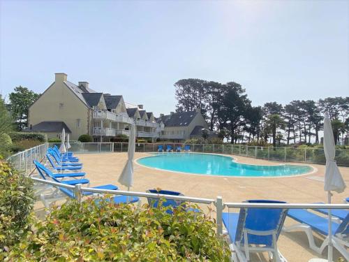 une piscine avec des chaises bleues et des parasols dans l'établissement Appartement à Fouesnant avec piscine chauffée, proche plage et GR34 - FR-1-481-109, à Fouesnant