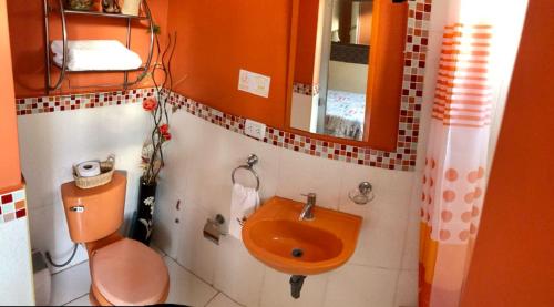 bagno con servizi igienici arancioni e lavandino di TRUJILLO GUESTHOUSE a Víctor Larco Herrera