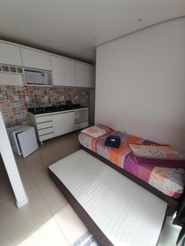 una pequeña cocina con 2 camas en una habitación en JK QUITINETES Executive GARAGEM central, en Pelotas