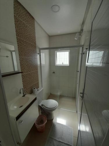a bathroom with a toilet and a sink and a shower at JK SUÍTES GARAGEM central in Pelotas