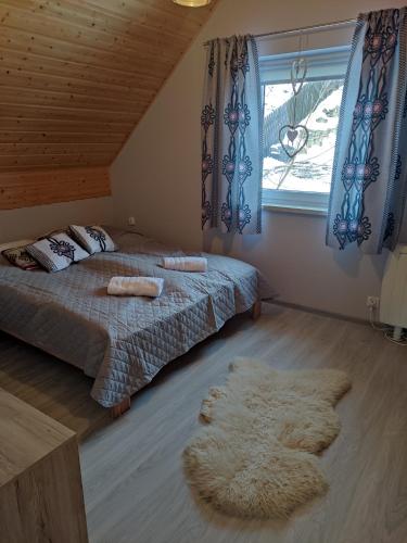 a bedroom with a bed and a window and a rug at Domek Jarmuta in Szlachtowa