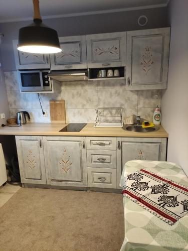 a small kitchen with white cabinets and a sink at Domek Jarmuta in Szlachtowa