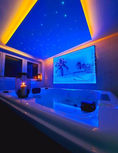 La grande salle de bains est pourvue d'une baignoire et d'une télévision murale. dans l'établissement Le doux refuge - SPA privatif - Romantique - Calme, à Châteauroux