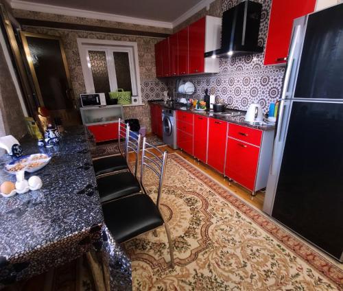 a kitchen with red cabinets and a black refrigerator at Heyvah - Guest House in Tashkent in Tashkent