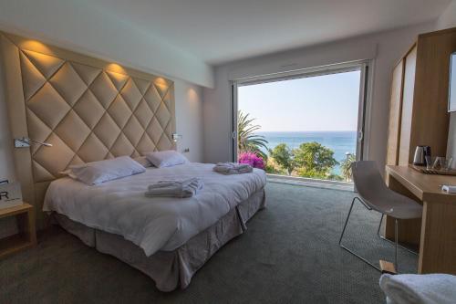 een hotelkamer met een groot bed en een groot raam bij Hotel Villa R in Calvi