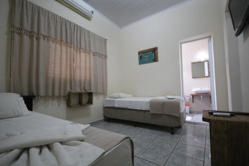 a hotel room with two beds and a window at Pousada Tia Nena in Olímpia