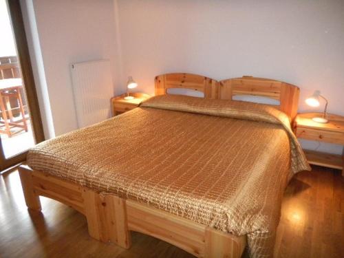 1 dormitorio con 1 cama de madera y 2 mesitas de noche en APPARTAMENTO Villa Isabella, en Bianzone
