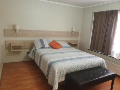 a bedroom with a bed with an orange pillow on it at Metro Pedro de Valdivia, Providencia. Departamento amplio 2 ambientes. in Santiago