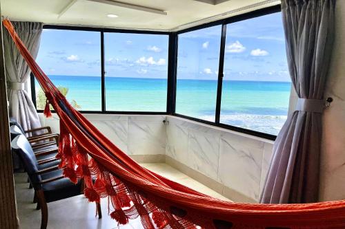 a hammock in a room with a view of the ocean at Atlântico Flat in Natal