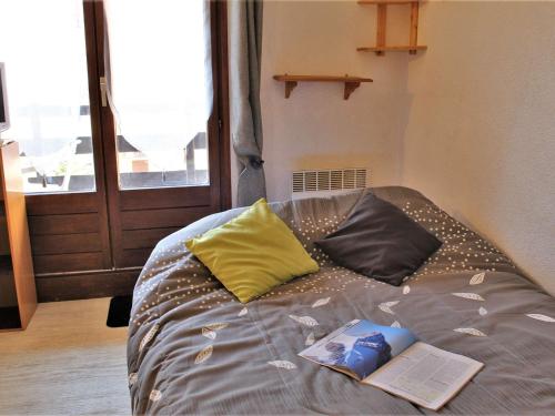 a bed with two pillows and a book on it at Appartement Risoul, 1 pièce, 4 personnes - FR-1-330-61 in Risoul