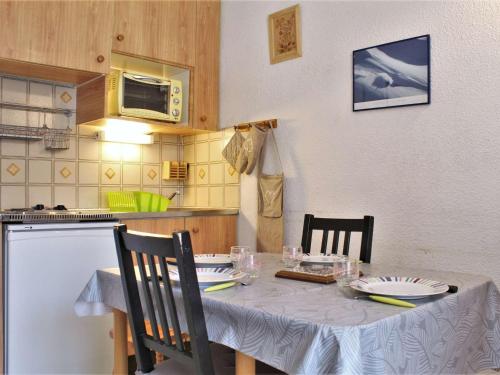 une cuisine avec une table, des chaises et une nappe dans l'établissement Studio cosy avec coin montagne, balcon sud et casier à ski - 4 couchages à Risoul 1850 - FR-1-330-61, à Risoul