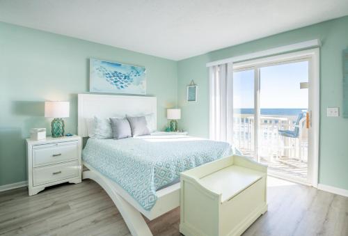a blue bedroom with a bed and a window at Oceanfront Condo with 3+ Pools - Ocean Dunes 1307 in Kure Beach