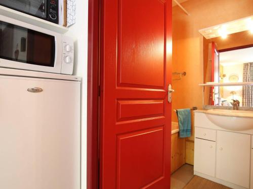 a red door in a kitchen with a microwave at Appartement Pelvoux, 2 pièces, 6 personnes - FR-1-330G-83 in Pelvoux