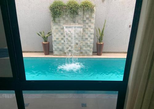 a swimming pool with a fountain with potted plants at Villa Das Conchas in Palhoça