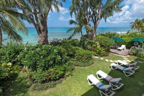 einen Rasen mit Stühlen und das Meer im Hintergrund in der Unterkunft La Paloma by Blue Sky Luxury in Saint James