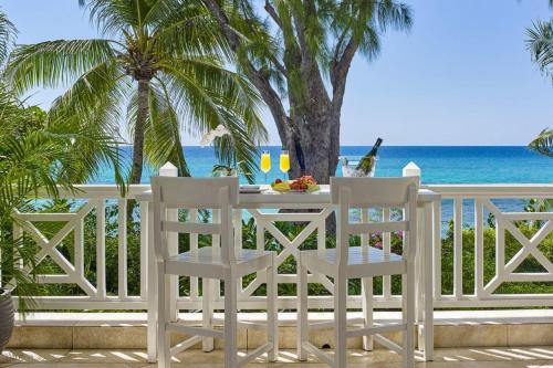 ein weißer Tisch und Stühle auf einem Balkon mit Blick auf das Meer in der Unterkunft La Paloma by Blue Sky Luxury in Saint James