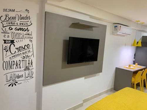 Habitación con TV en la pared y cama amarilla. en Manaíra Apart Hotel 1505, en João Pessoa