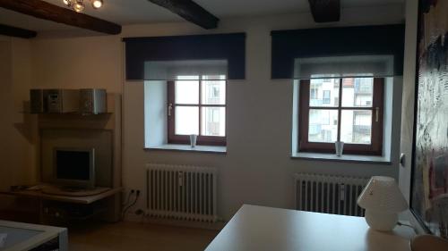 a living room with three windows and a television at Apartment Regensburg in Regensburg