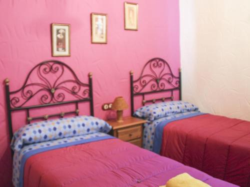 Dos camas en una habitación con paredes rosas. en Cortijo Lagarín, en El Gastor