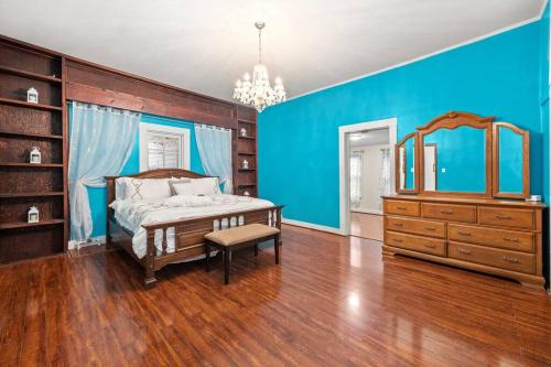 Schlafzimmer mit blauen Wänden, einem Bett und einem Spiegel in der Unterkunft Fully Restored Country Manor 
